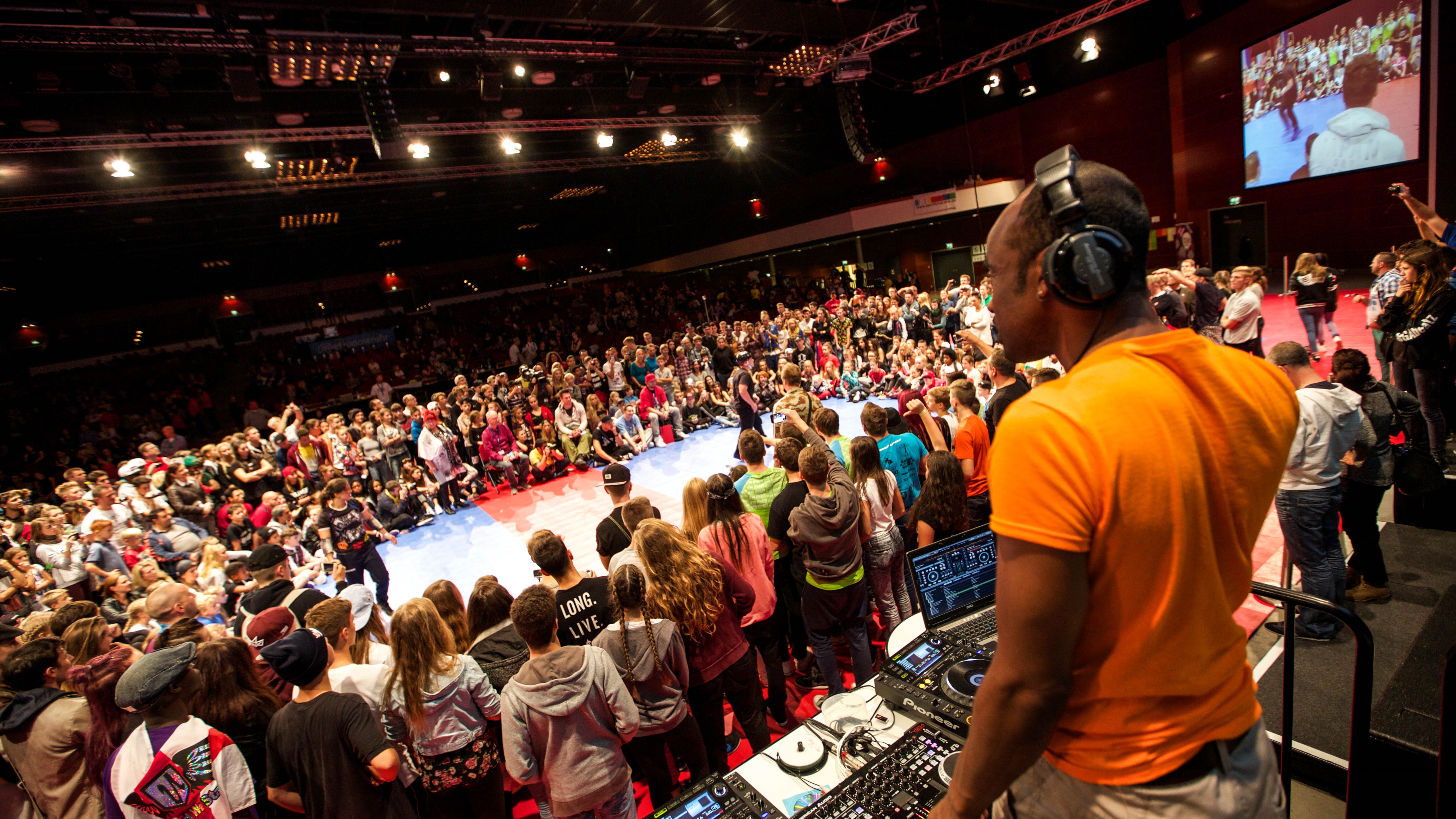 HipHop WM im RuhrCongress Bochum. Die Zuschauer bilden einen Kreis um die Bühne. Im Vordergrund ist der DJ zu sehen.